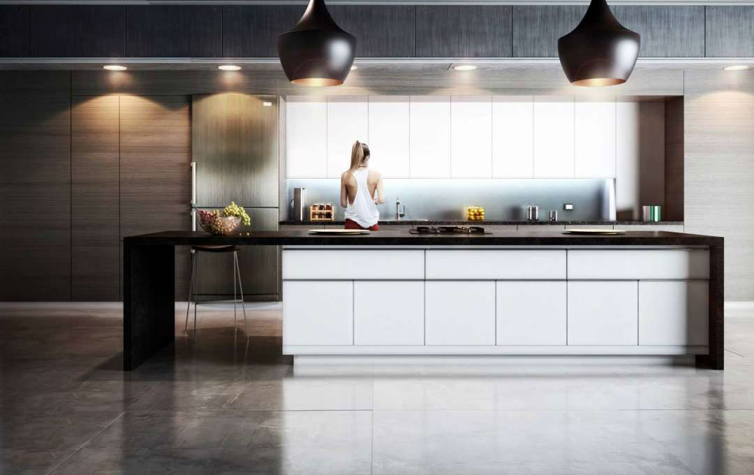 Modern kitchen with sleek white cabinets, dark countertops, and a woman facing away.